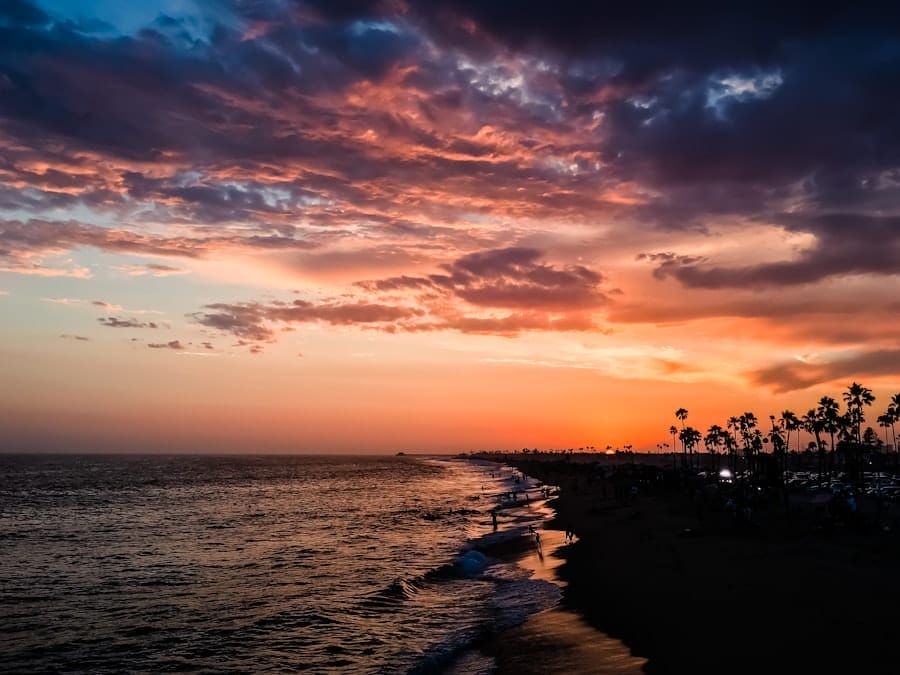 A vibrant sunset over the ocean with a sandy beach in the foreground.